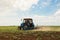 Tractor cultivating field of ripening sunflowers. Agricultural industry