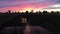 Tractor cultivating field at spring, aerial sunset view