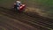 Tractor cultivating field at spring, aerial sunset view