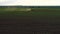 Tractor cultivating field at spring, aerial sunset view