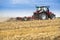 Tractor cultivating wheat stubble field, crop residue.