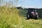 The tractor cuts the grass on the meadow. Focus on grass.