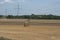 Tractor in the distance, harrowing a field after the summer harvest and throwing up dust clouds, with a bales of straw in the fore