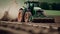 A tractor drives on a green field, plowing the soil, preparing to plant new crops