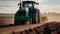 tractor drives on a green field, plowing the soil, preparing to plant new crops
