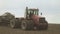 Tractor with eight wheels and a trailed hopper for grain on field.