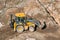 Tractor excavator with bucket rides running through mud lands setting, view from the height.