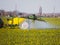 Tractor fertilizes a canola , spraying fertilizer with a tractor