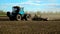 The tractor on the field cultivates the soil. Selective focus.