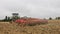 Tractor in a field cultivating the soil in preparation for seeding. UK