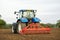 Tractor in a field preparing the soil for seed drilling. UK