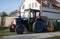 Tractor on the front lawn. Blue agricultural tractor for cultivating the land