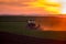 Tractor harrowing field at sunset