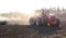 Tractor harvesting and soil cultivation for subsequent sowing. Field and dust in the sun, work in agriculture