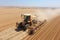 Tractor harvests in the wheat field in autumn, aerial view