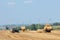 Tractor hauling a round bale an open field with blue sky.