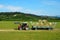 A tractor with its trailer loaded with hay bales