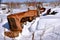 Tractor in a junkyard partially buried in snow