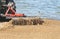 Tractor with large metal rake attached sifting, raking and clearing debris at a public beach in early morning