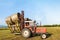 Tractor lifting hay bale on barrow.