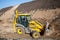 Tractor loader backhoe digger loader on a construction site with blue sky and dramatic clouds