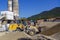 Tractor-loader loads rubble on a bright Sunny day. Piles of rubble.  In the background, the shop for the production of concrete.