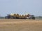 Tractor loading large round hey bails onto semi truck trailer for transport