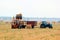 Tractor loads bays of hay on the harvested field