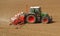 Tractor with a modern sowing seeds machine in a newly plowed field in springtime. Side view. Plowed land on background