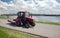 Tractor moves down on a road against city landscape