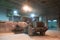 Tractor moves the sand in the cement plant. Dark room with lights