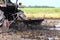 Tractor moves through a wet puddle mud black, tractor ploughing at rice field and splash of muddy wet, mud from a tractor