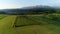 Tractor mowing the grass with beautiful high mountains in the background, aerial view.