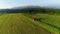 Tractor mowing the grass with beautiful high mountains in the background, aerial view.