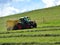 Tractor mowing grass on a sloping meadow in midsummer