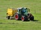 Tractor mowing grass on a sloping meadow in midsummer