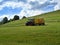 Tractor mowing grass on a sloping meadow in midsummer