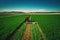 Tractor mowing green field, aerial view