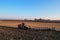 Tractor with Plough on Plowed. Ploughing and Soil Tillage. Agricultural Tractor on Cultivation Field for Sowing Seeds. Big Tractor