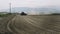 Tractor plowing a dusty field with people see