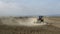 Tractor plowing a dusty field with unrecognizable people