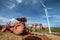 Tractor plowing in plantation farm with wind turbines clean energy electricity.