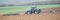 A tractor plowing and sowing in the field. Panoramic format