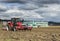 Tractor plows the field in front of some agricultural buildings on a sunny spring day