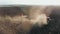 The tractor plows the field in sunset, raising dust, and behind it fly birds. Aerial view. Agriculture industry