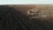 Tractor plows the field in sunset, sunrise, raising dust, and behind it fly birds. Aerial shot. Farm tractor with harrow