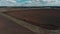 The tractor plows the ground on the field at the beginning of the planting season. Aerial view 4K