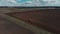 The tractor plows the ground on the field at the beginning of the planting season. Aerial view 4K