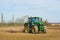 Tractor preparing soil in a field for spring sowing. Hertfordshire UK