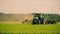 Tractor is protecting wheat with herbicide spraying, Plant protection spraying herbicides.